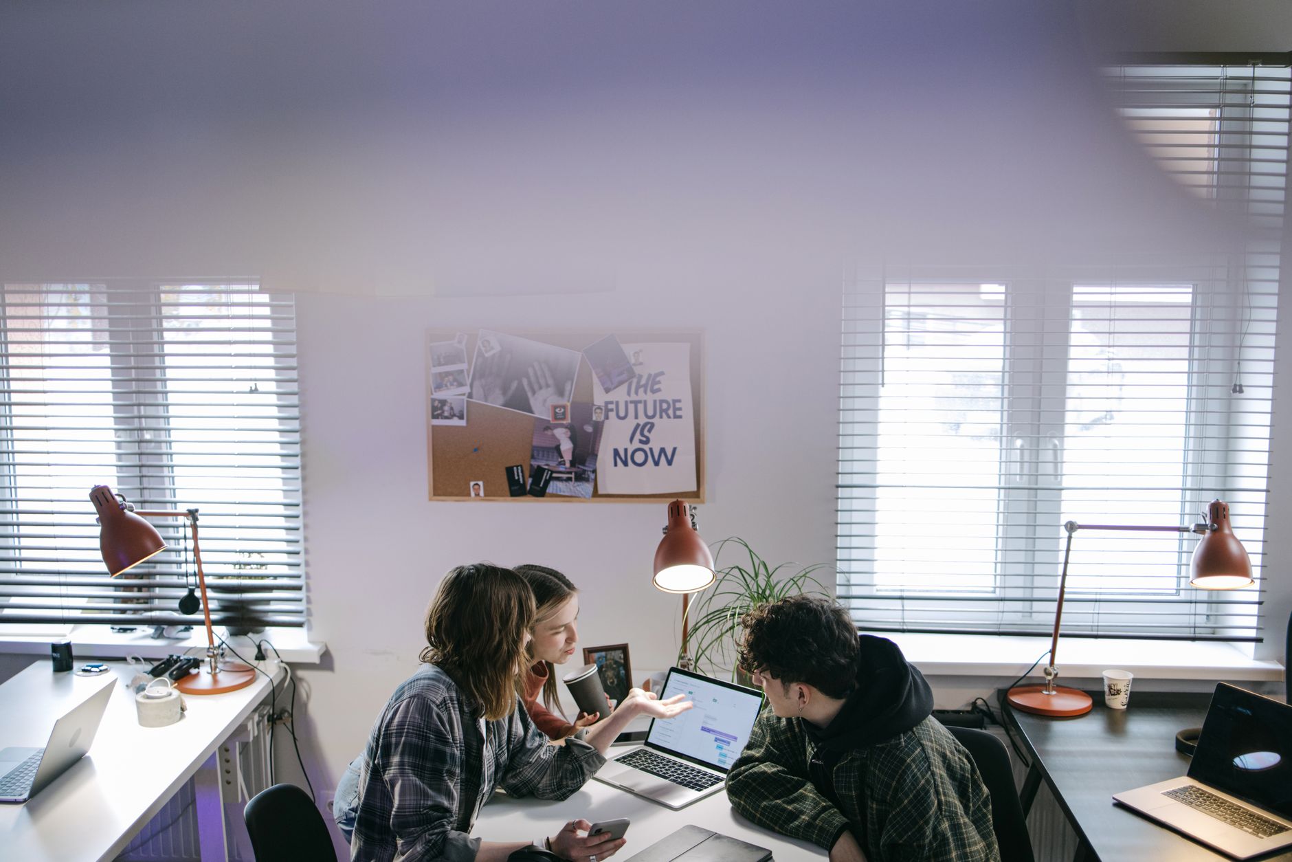 A group of people discussing ideas around laptops in a bright, modern office space — illustrating: Cybersecurity Solutions for Central Florida SMBs: Essential Protection for Tampa Bay Businesses